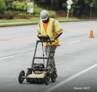 A man using a machine on a road to detect for subsurface utilities